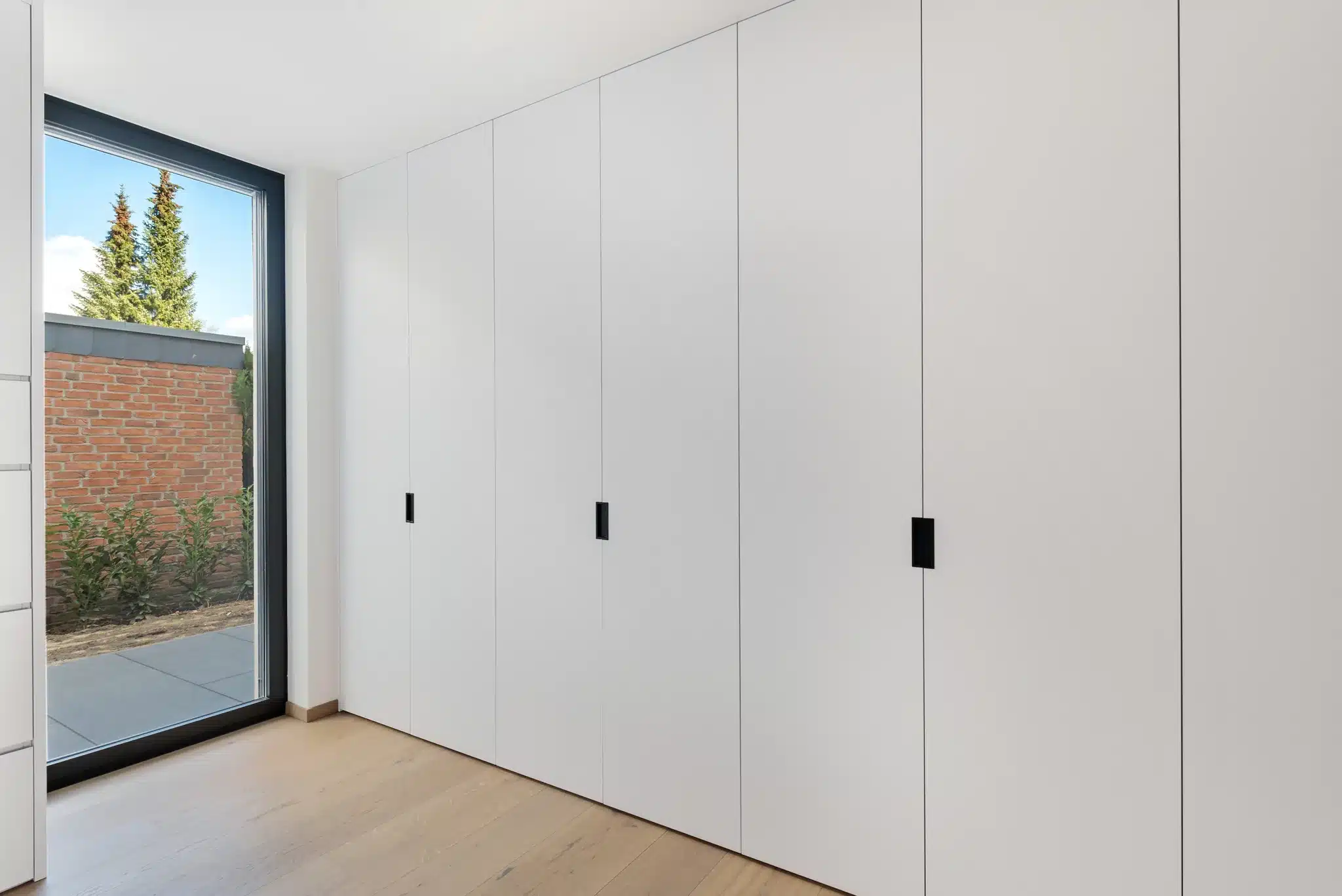 Einbauschrank nach Maß in Düsseldorf – raumhohe Fronten mit Griffmulden und Passleisten