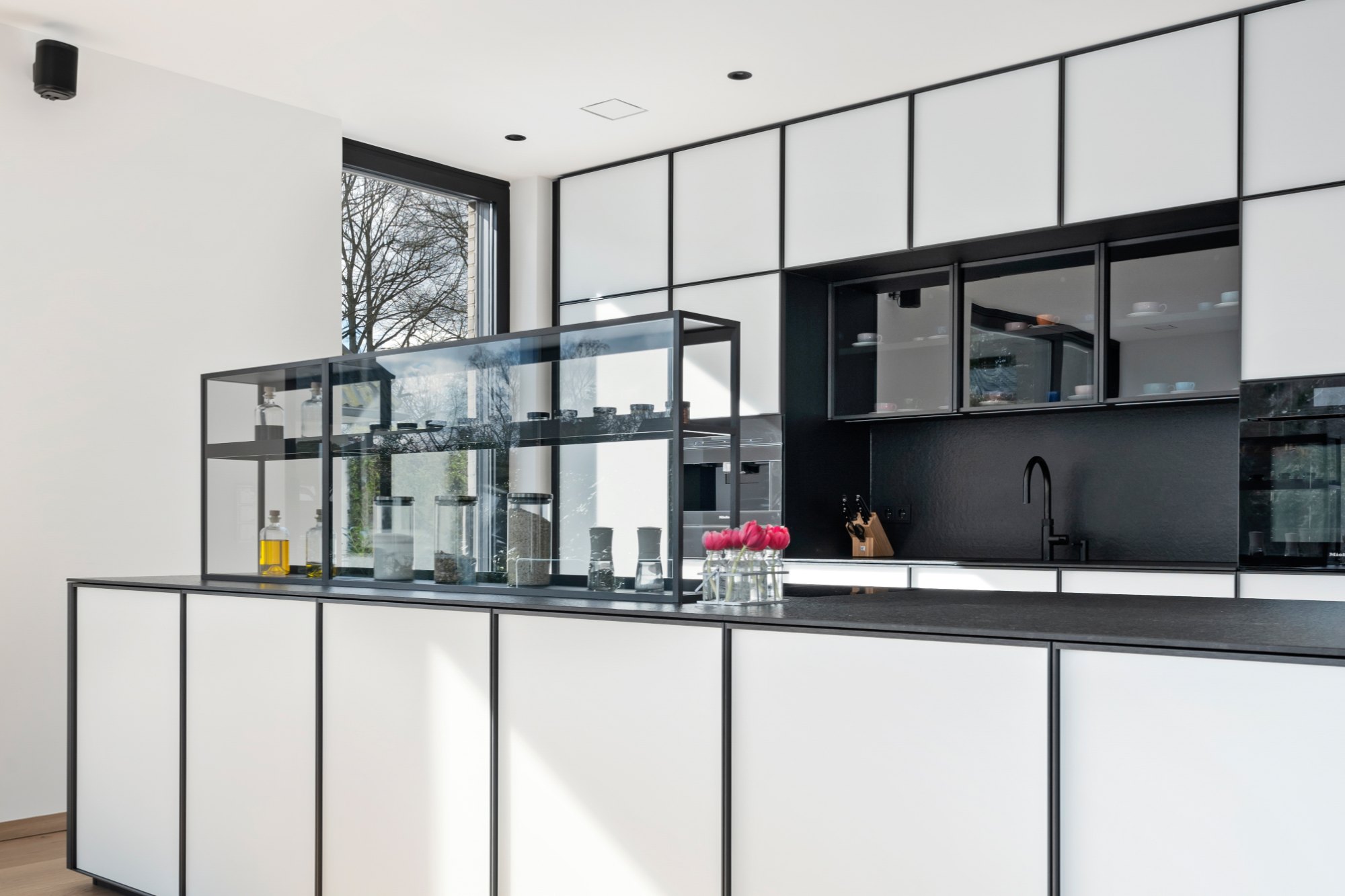 Hauseinrichtung Hamburg von HOME Schlafen & Wohnen: Küche mit Glasvitrine im schwarzen Rahmen