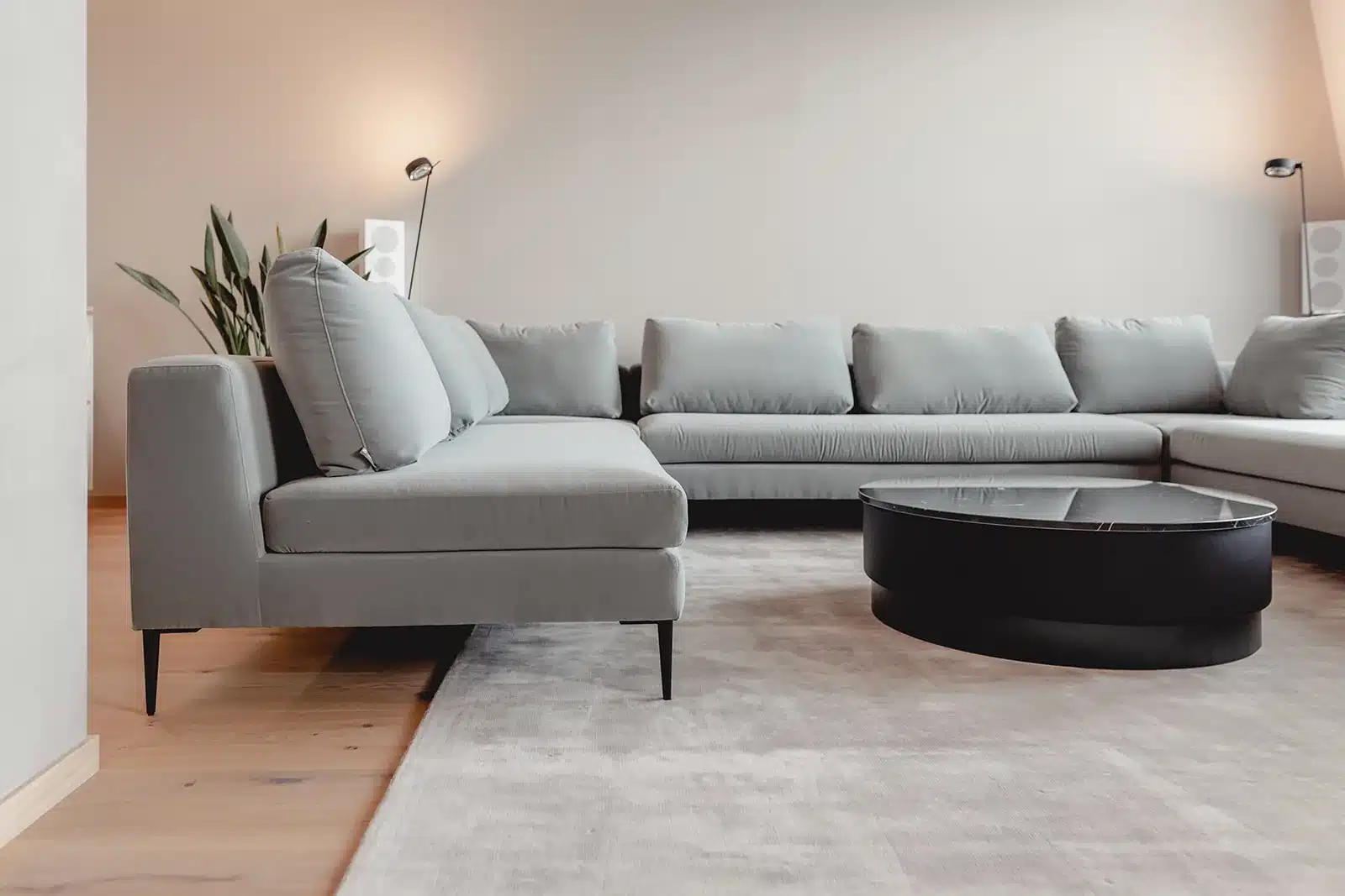 Wohnzimmer mit großem Ecksofa und rundem Couchtisch, eingerichtet von HOME
