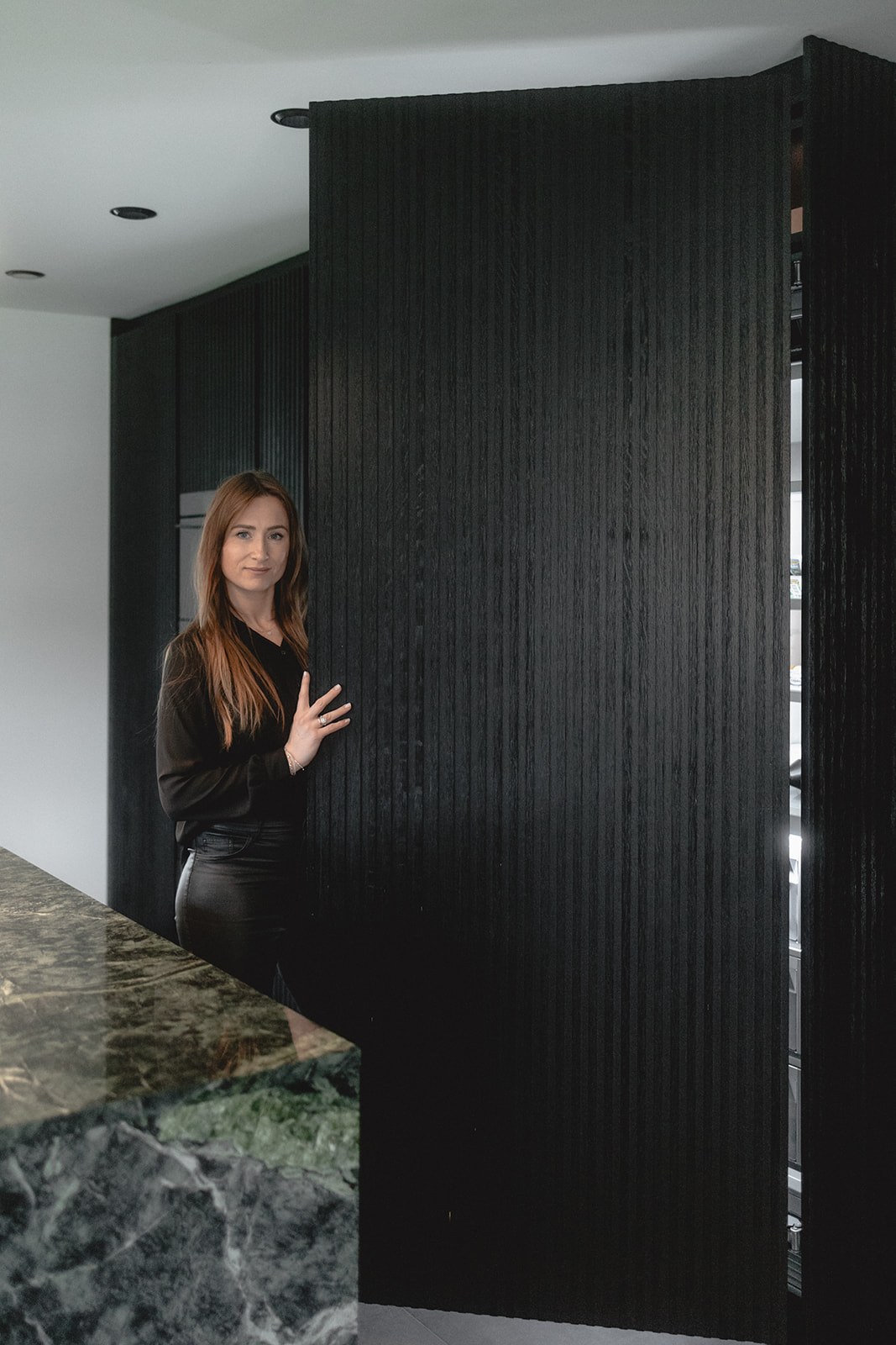 Laura Mollidor von HOME öffnet die raumhohe Tür aus geriffelter Räuchereiche vor dem extrabreiten Kühlschrank