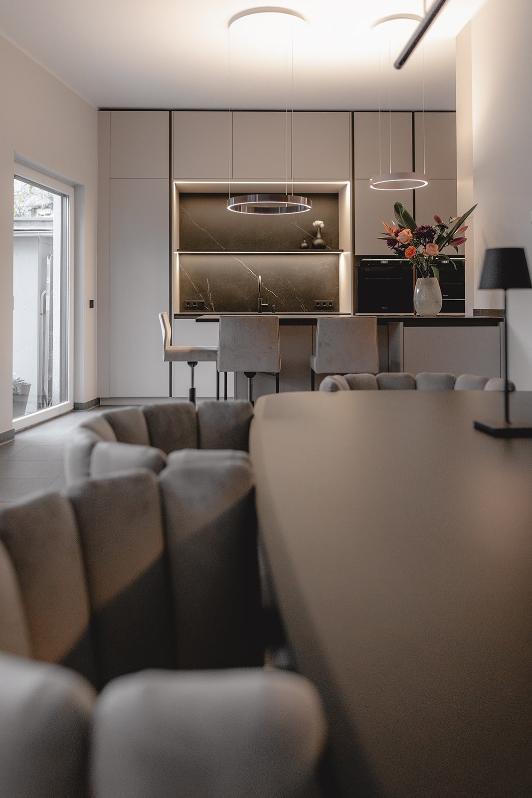 Wohnung Köln von HOME Schlafen & Wohnen: Kücheninsel und Sofa im offenen Raum