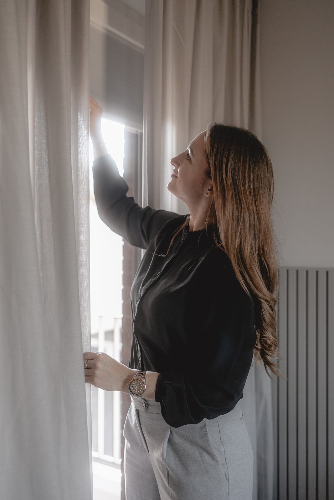 Laura Mollidor von HOME öffnet die Gardine in der Wohnung in Leverkusen
